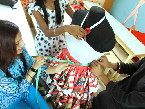 A Picture of IIFT students taking measurements of a dress on a mannequin as part of their Lab Activity